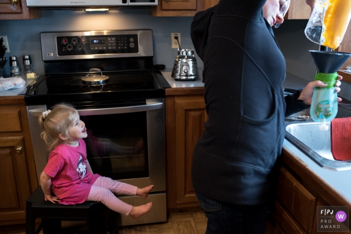 A young girl lickin' her chops while 'helping' mom in the kitchen. 