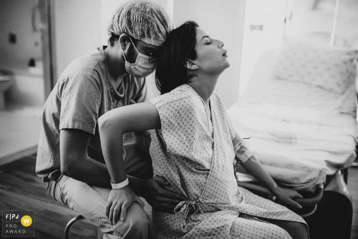 Photo by: <a href="https://www.fpja.com/documentary-family-photography-contests/ellen-brito/sao-paulo/2106943">Ellen Brito - Brazil</a> Hospital e Maternidade São Luiz birth image of a woman in labor with her husband holding her