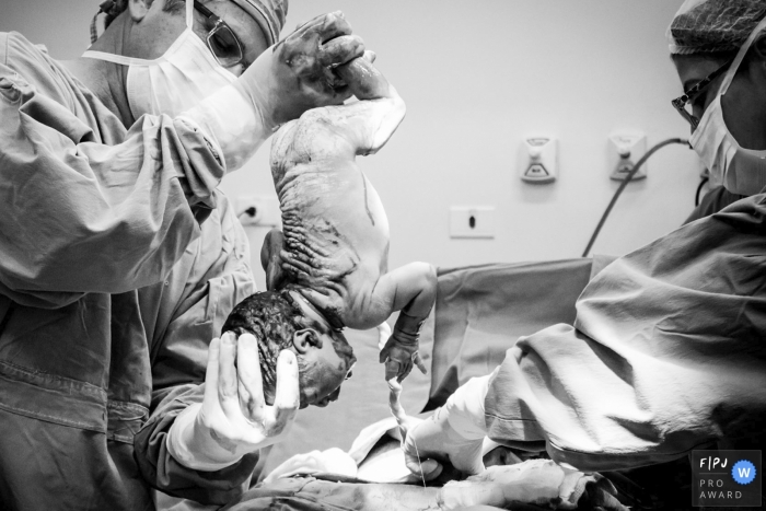 Photo by: <a href="https://www.fpja.com/documentary-family-photography-contests/lukinha-arruda/arapongas/2107012">Lukinha Arruda - Brazil</a> Hospital Santa Casa Birth Photography | Doctor removing baby upside down