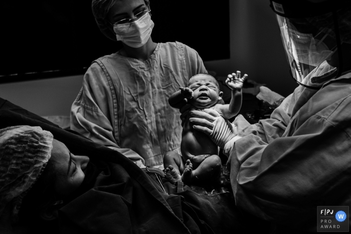 Brazilian Birthing image | the newborn is lifted up as mom takes a peek