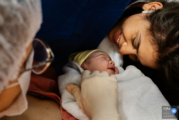 Photo by: <a href="https://www.fpja.com/documentary-family-photography-contests/marcos-paulo/sao-paulo/2107163">Marcos Paulo - Brazil</a> Sao Paulo birth image of smiling mom and infant with a cute smile back
