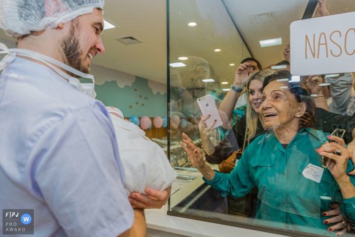 Photographie de naissance périnatale de Laranjeiras | Les visiteurs jettent un œil au nouveau bébé, grand-mère avec la vue au premier rang