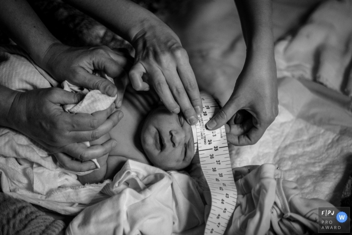 Photo by: <a href="https://www.fpja.com/documentary-family-photography-contests/cibele-barreto-mendes/sao-paulo/2108003">Cibele Barreto Mendes - Brazil</a> Sao Paulo At-Home Birth Photo of a baby having its head measured