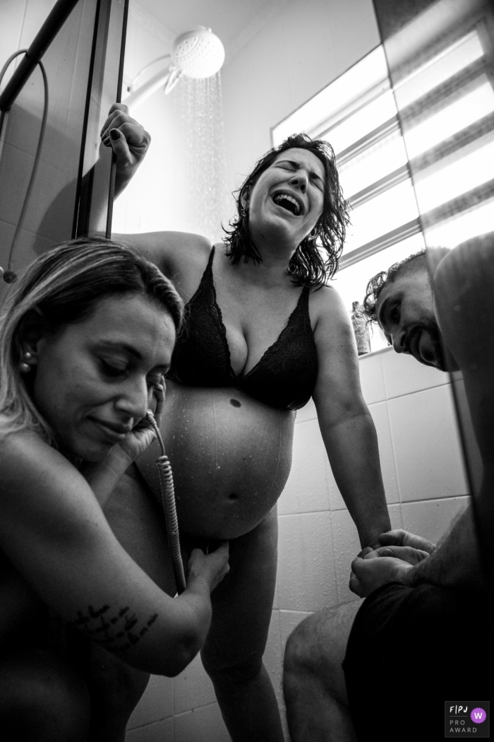 Photo by: <a href="https://www.fpja.com/documentary-family-photography-contests/cibele-barreto-mendes/sao-paulo/2108013">Cibele Barreto Mendes - Brazil</a> Sao Paulo at-home birth photo of midwife listening to baby's heartbeat