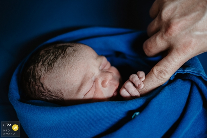 Photo by: <a href="https://www.fpja.com/documentary-family-photography-contests/thiago-braga/florianopolis/2108255">Thiago Braga - Brazil</a> Maternidade Santa Helena birth image of the newborn boy holding on to his father's finger