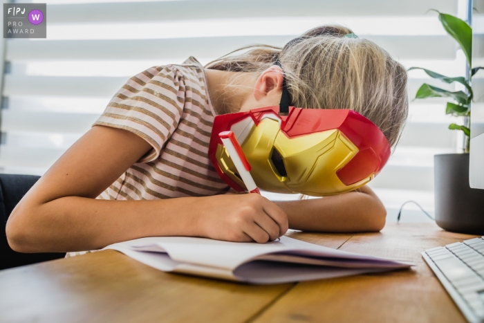 Limburg Family Photo showing a Girl works on her homework while wearing an Iron Man mask Limburg Family Photographer | Girl works on her homework while wearing an Iron Man mask