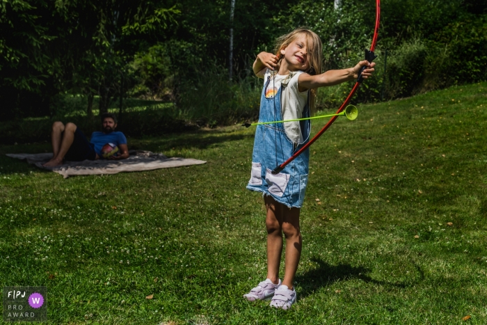 Photo by: <a href="https://www.fpja.com/documentary-family-photography-contests/kobe-vanderzande/limburg/2106641">Kobe Vanderzande - Belgium</a> Limburg Family photo of girl misfiring the arrow