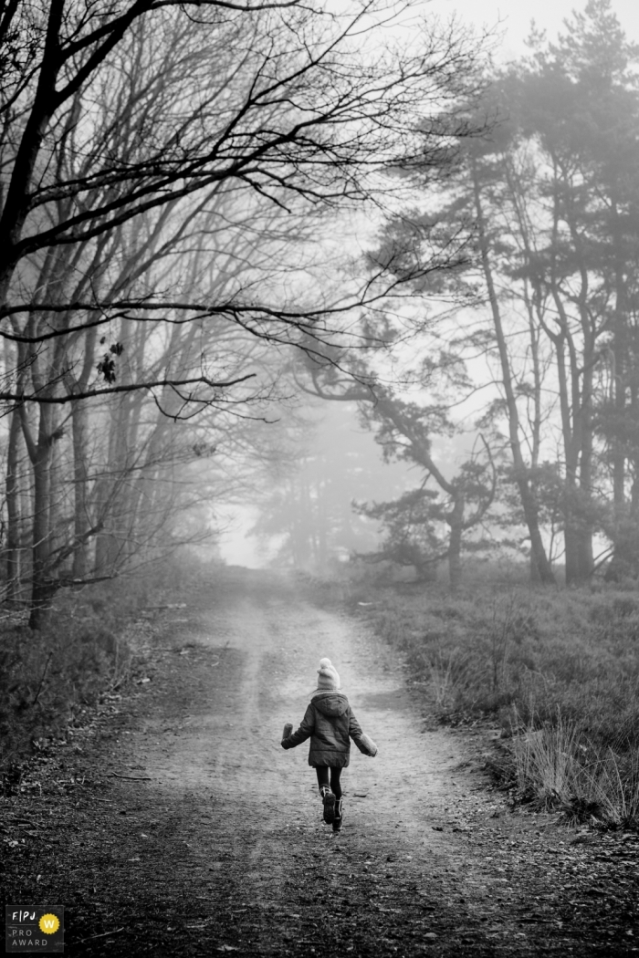 Photo de famille du Limbourg d'une jeune fille prenant une promenade d'hiver sur une route bordée d'arbres