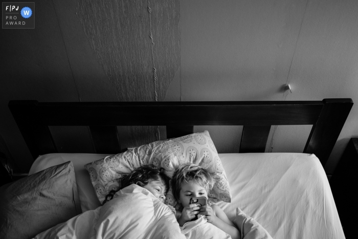Photo by: <a href="https://www.fpja.com/documentary-family-photography-contests/jess-haverkamp/berlin/2106722">Jess Haverkamp - Germany</a> Berlin Family Session | Sneaking onto the phone in the morning.