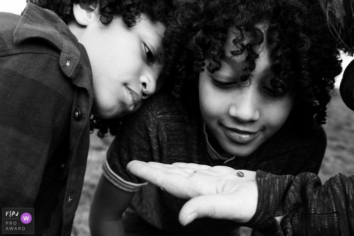 Photo by: <a href="https://www.fpja.com/documentary-family-photography-contests/lavinia-nitu/modena/2106979">Lavinia Nitu - Italy</a> Modena Documentary Family Photography | brothers look closely at at tiny snail