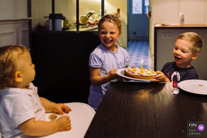 Paris Documentary Family photo of siblings arriving at the table with a cake and one single candle to their younger brother