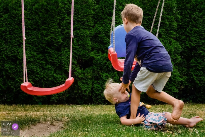 Photo by: <a href="https://www.fpja.com/documentary-family-photography-contests/katrin-k%C3%BCllenberg/dusseldorf/2107592">Katrin Küllenberg - Germany</a> NRW Documentary Family Photography | a boy arrives to help his toddler brother after slipping off the swing and landing to the ground