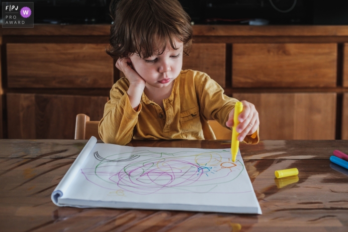 Little boy coloring at the table during this documentary family session in Belgium Little boy coloring at the table during this documentary family session in Belgium