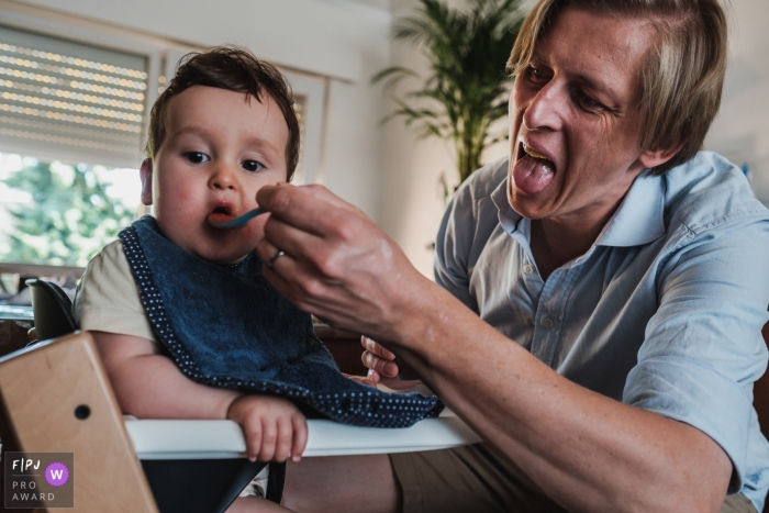 Photo by: <a href="https://www.fpja.com/documentary-family-photography-contests/christophe-de-mulder/antwerpen/2107722">Christophe De Mulder - Belgium</a> Antwerpen Documentary Family photography of a father feeding his son, and making weird faces