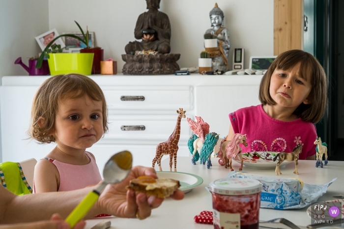 Photo by: <a href="https://www.fpja.com/documentary-family-photography-contests/nadine-court/savoie/2107741">Nadine Court - France</a> France Documentary Family image of two sisters at the table for breakfast