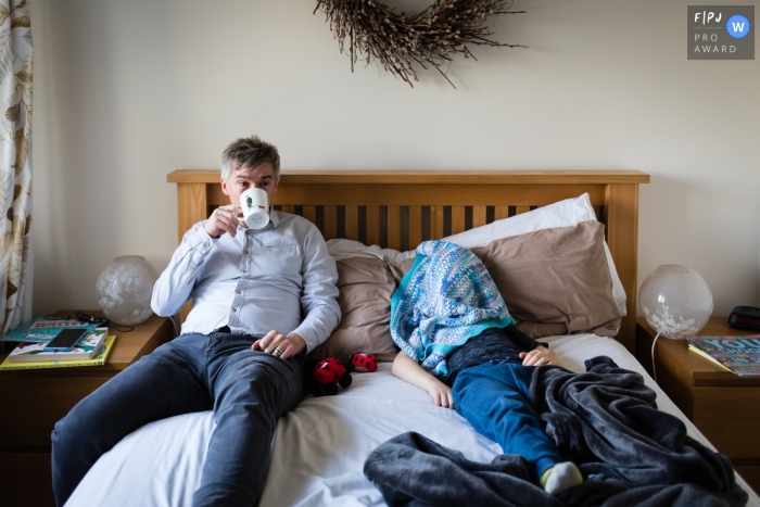 Cambridgeshire Documentary Family Photo de papa buvant du thé au lit pendant que le garçon se cache sous une couverture