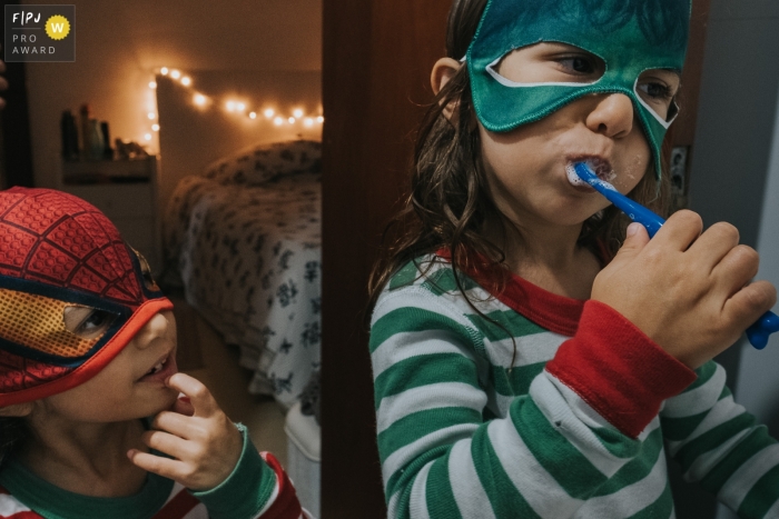 Sao Paulo Documentary Photographer | sisters dressed as super heroes before bed time, one brushing their teeth