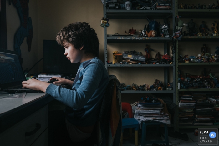 Photo by: <a href="https://www.fpja.com/documentary-family-photography-contests/raquel-oczerny/sao-paulo/2108170">Raquel O'Czerny - Brazil</a> Sao Paulo Documentary Family Photography of a teenager playing on the computer and has forgotten all about his toys
