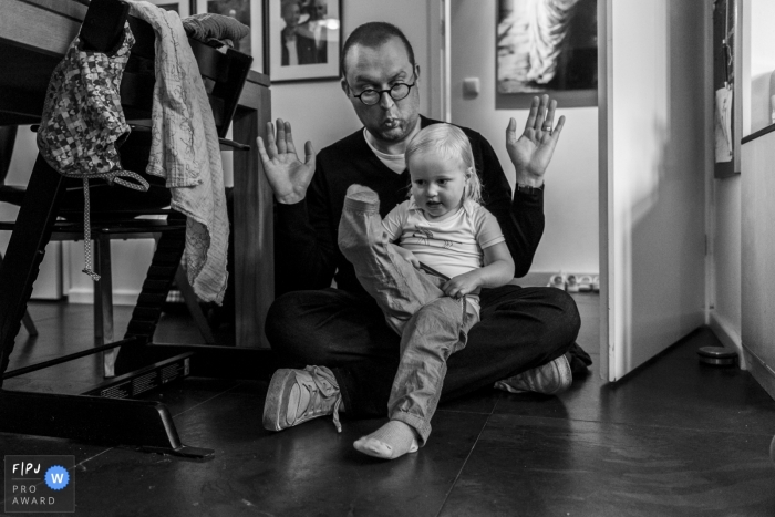 Noord Holland Family Photographer | young girl sitting in her father's lap is insistent upon getting dressed all by herself