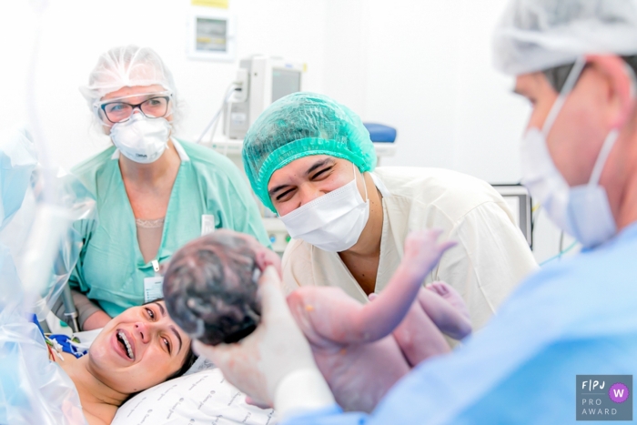 Maternidade Santa Joana Birth photograph of a father looking into the face of his newborn as the doctor holds him up