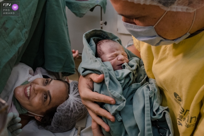 MG hospital documentary-style baby birth photo shoot of father holding his new baby at Maternidade Femina