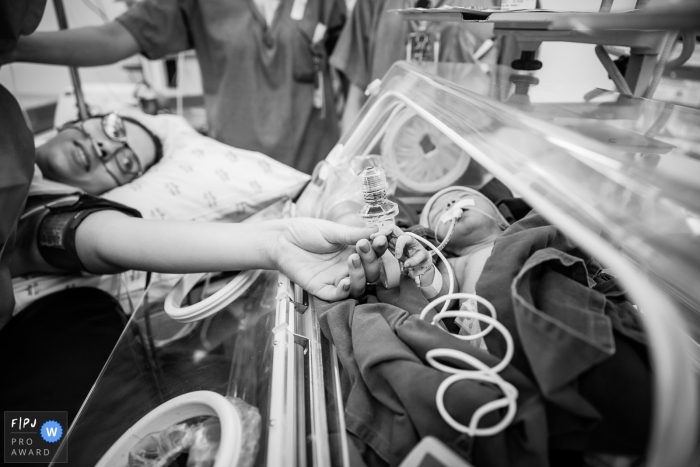 Photo by: <a href="https://www.fpja.com/documentary-family-photography-contests/gab-campello/sao-paulo/2109768">Gab Campello - Brazil</a> SP mom/baby hospital birth photography at Hospital e Maternidade São Luiz Unidade Itaim of mom reaching to her newborn in his bed