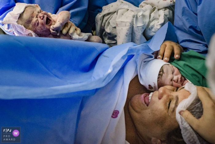 Photo by: <a href="https://www.fpja.com/documentary-family-photography-contests/clara-sampaio/rio-de-janeiro/2110205">Clara Sampaio - Brazil</a> Perinatal Barra da Tijuca birth photograph of a mother smiling after giving birth to twins