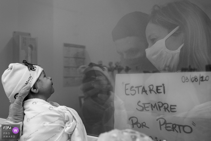 Photo by: <a href="https://www.fpja.com/documentary-family-photography-contests/cibele-piovesan/sao-paulo/2110256">Cibele Piovesan - Brazil</a> Newly born baby is shown through the windows of the nursery at the hospital as the visitors look upon him at Pro Matre