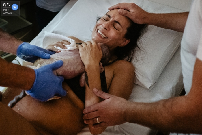 Photo by: <a href="https://www.fpja.com/documentary-family-photography-contests/thiago-braga/florianopolis/2110363">Thiago Braga - Brazil</a> Maternidade Santa Helena birth image, from Santa Catarina Photographer: "Every feeling of the mother when receiving her child from the doctor's hands in her arms in a natural delivery, very fast, full of emotions.