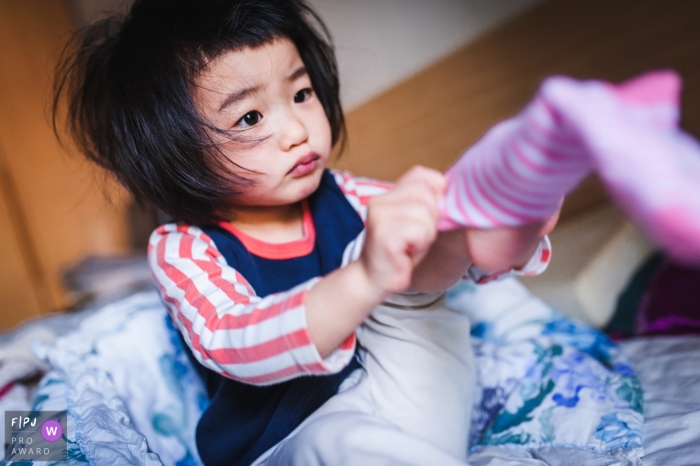 Photo by: <a href="https://www.fpja.com/documentary-family-photography-contests/micky-zhou/hunan/2108436">Micky Zhou - China</a> Hunan China family photo of a girl putting on her socks at home