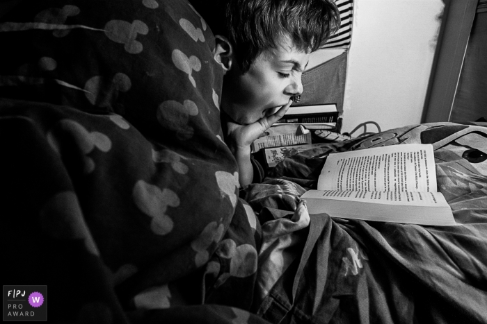 Photo by: <a href="https://www.fpja.com/documentary-family-photography-contests/emilie-marchandise/2108584">Emilie Marchandise - Belgium</a> DITL Belgium family photography of boy in bed reading at the end of his day in Brabant Wallon