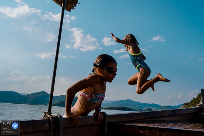 Wallonie family photography session at the water of girl jumping from a dock and one girl climbing out