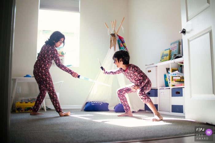 Florida Brothers have a sword fight in their playroom while mom is asking them to go upstairs and get dressed for their day in this Sarasota	family photography