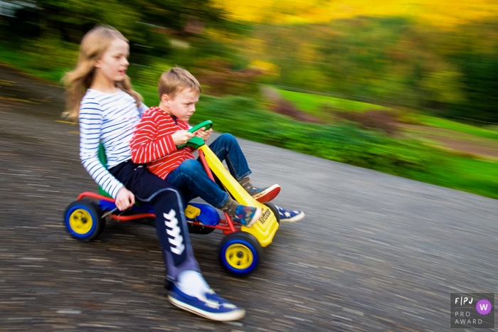 North Rhine-Westphalia family photography showing a Brother and sister on a kettcar in Dusseldorf North Rhine-Westphalia family photography showing a Brother and sister on a kettcar in Dusseldorf