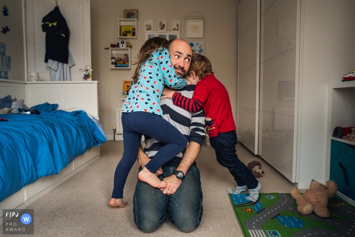England family photos from an at-home session of dad being jumped on by his two children in County Durham England family photos from an at-home session of dad being jumped on by his two children in County Durham