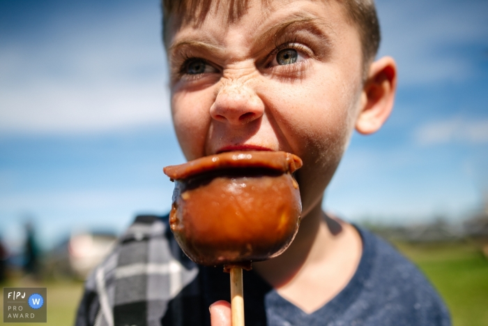 Kingston family photography session outdoors of boy eating a candied apple