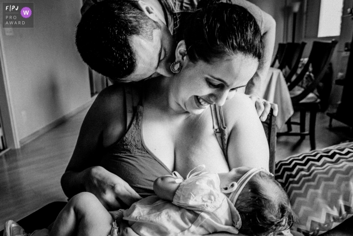 Photo by: <a href="https://www.fpja.com/documentary-family-photography-contests/thiago-gimenes/sao-paulo/2108972">Thiago Gimenes - Brazil</a> SP documentary-style newborn and family photography session of a mom breastfeeding her daughter as dad sneeks in a kiss to his wife