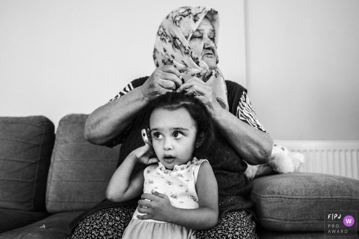 Black and white Istanbul documentary-style family photography session of a grandmother helping out her granddaughter