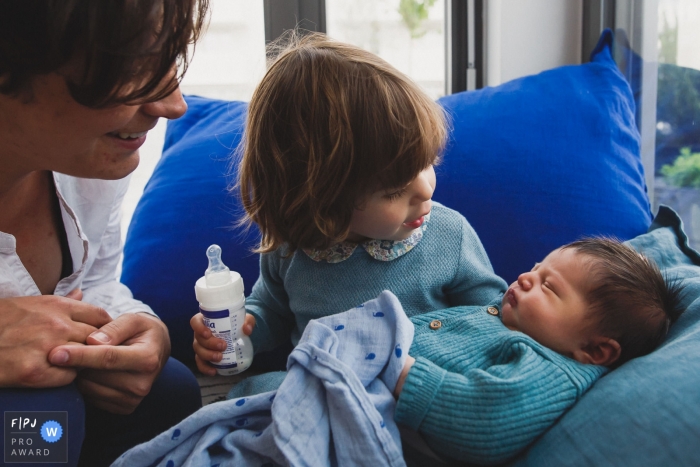 Photo by: <a href="https://www.fpja.com/documentary-family-photography-contests/annie-gozard/paris/2109132">Annie Gozard - France</a> Paris family/newborn image session in the home of a young girl preparing to feed her new sibling a bottle in France