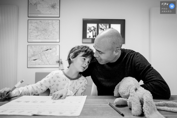 Photo by: <a href="https://www.fpja.com/documentary-family-photography-contests/sybil-rondeau/nantes/2109237">Sybil Rondeau - France</a> Nantes black and white father/child image shoot in the home during Homework time