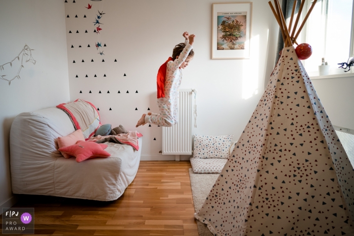 Photo by: <a href="https://www.fpja.com/documentary-family-photography-contests/sybil-rondeau/nantes/2109238">Sybil Rondeau - France</a> Nantes family photography from the home with a young boy Playing Superhero