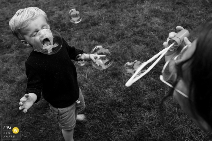 Young boy plays with mom blowing bubbles in this Seattle family photo