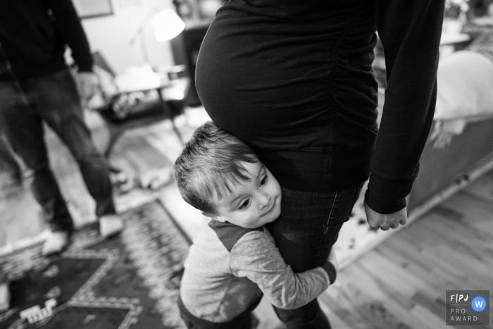 Photo by: <a href="https://www.fpja.com/documentary-family-photography-contests/ron-storer/seattle/2109717">Ron Storer - United States</a> A boy hugs his pregnant momma in this Seattle Family image