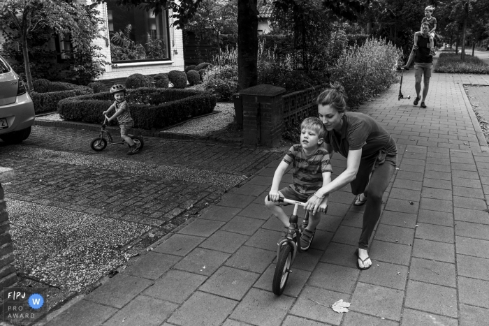 Photo by: <a href="https://www.fpja.com/documentary-family-photography-contests/gonda-meurs/noord-holland/2109885">Gonda Meurs - Netherlands</a> NL outdoor family pictures from an at-home photo shoot of a mother helping her son ride a bike for the first time