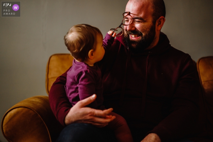 UK family image shoot in the home with toddler who is pulling her father's spectacles off of him