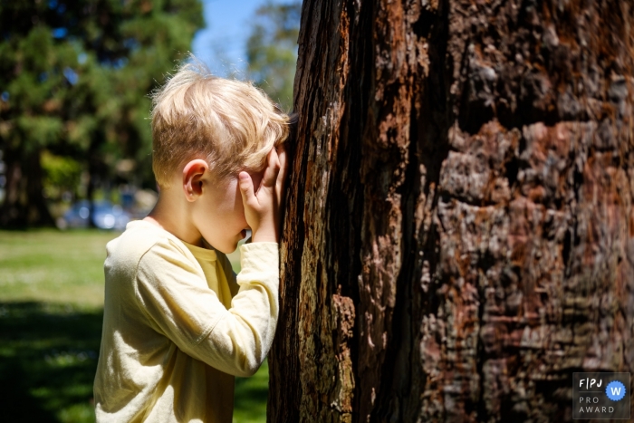 Young boy is playing hide and seek at the park in this San Francisco Family image Young boy is playing hide and seek at the park in this San Francisco Family image