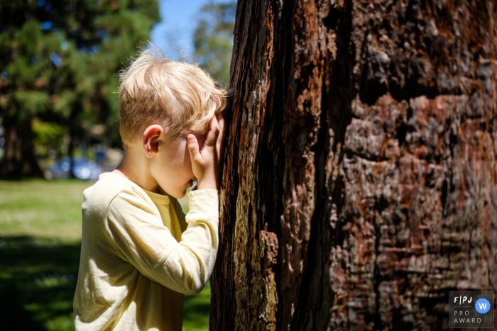 Young boy is playing hide and seek at the park in this San Francisco Family image