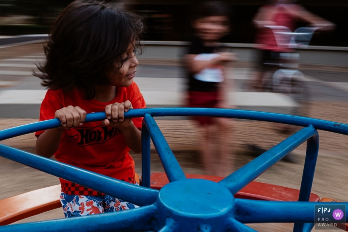 A child spins in a round-a-bout at a park during this Brazilian family photo shoot