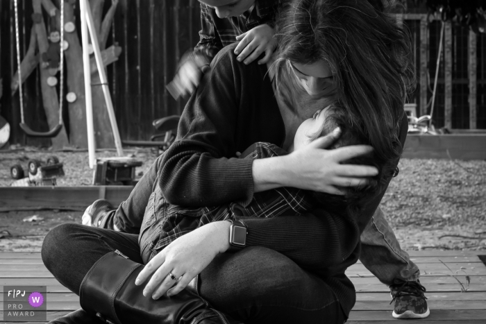 Photo by: <a href="https://www.fpja.com/documentary-family-photography-contests/loren-haar/ventura/2110314">Loren Haar - United States</a> Ventura Family Photographer captures a mother holding a child while a second child is drumming on her shoulder