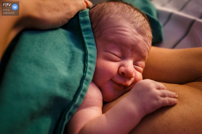 Photo by: <a href="https://www.fpja.com/documentary-family-photography-contests/adriana-costa/belo-horizonte/2110618">Adriana Costa - Brazil</a> Mater Dei hospital documentary birth photography showing baby with a happy countenance right after birth